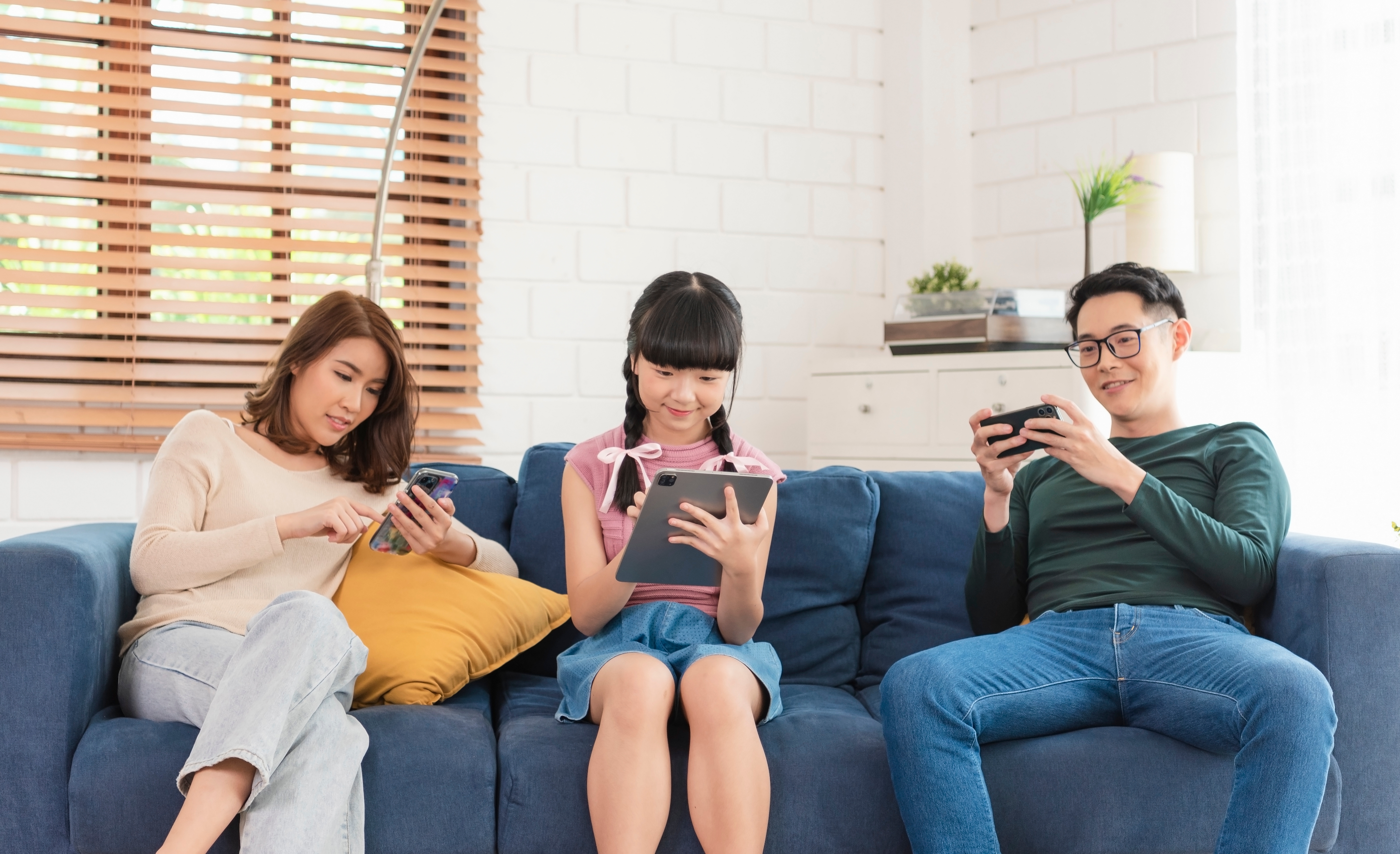 Asian family using tablet and mobile phones at home. addicted to devices, gadgets dependence overuse