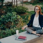 Peaceful calm redhead business woman doing yoga with closed eyes outdoor