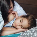 Woman with little sleeping girl in bed