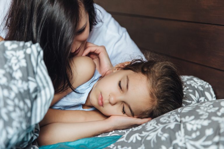 Woman with little sleeping girl in bed