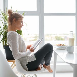 Young relaxed woman reading after healthy breakfast