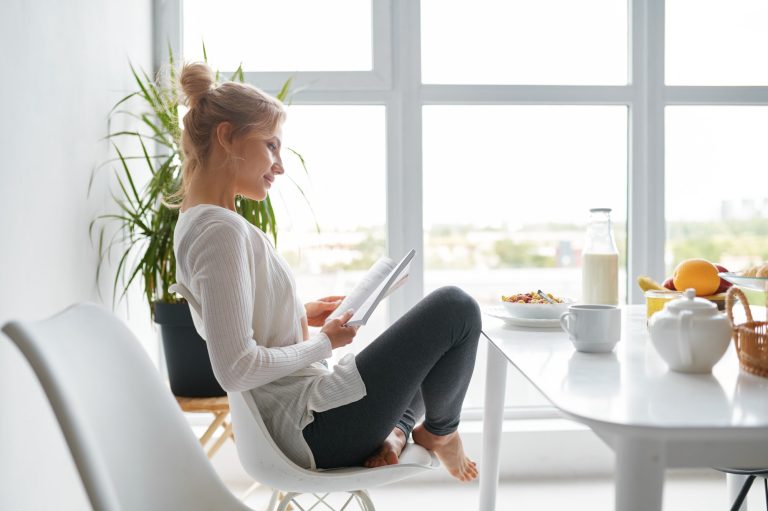 Young relaxed woman reading after healthy breakfast