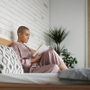 Young woman with cancer reading book, cancer awareness concept.